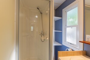 Een badkamer met een douchecabine van glas, een raam met gezandstraald glas en een houten wastafelmeubel.