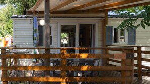 A wooden deck with outdoor seating, a covered area, and a sign indicating room number 1. - Mobile Home 'Mobil-home E - 1-6 Pers' with Shared Pool, Private Terrace and Shared Garden (Lavilledieu)