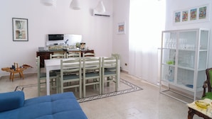 Un comedor con una mesa y sillas, un televisor y un mueble con cristalería.