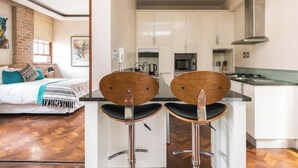 Una cocina compacta con gabinetes blancos, una campana extractora de acero inoxidable y una encimera.