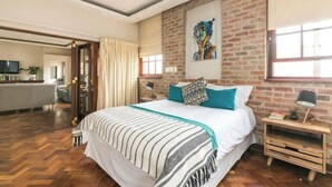 Un dormitorio moderno con una cama grande, una pared de ladrillo y un cuadro.