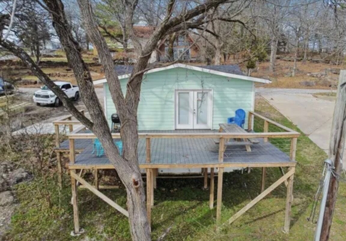 A small, single-story house with a porch and a covered deck area.
