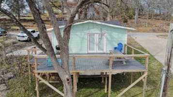 A small, single-story house with a porch and a covered deck area.