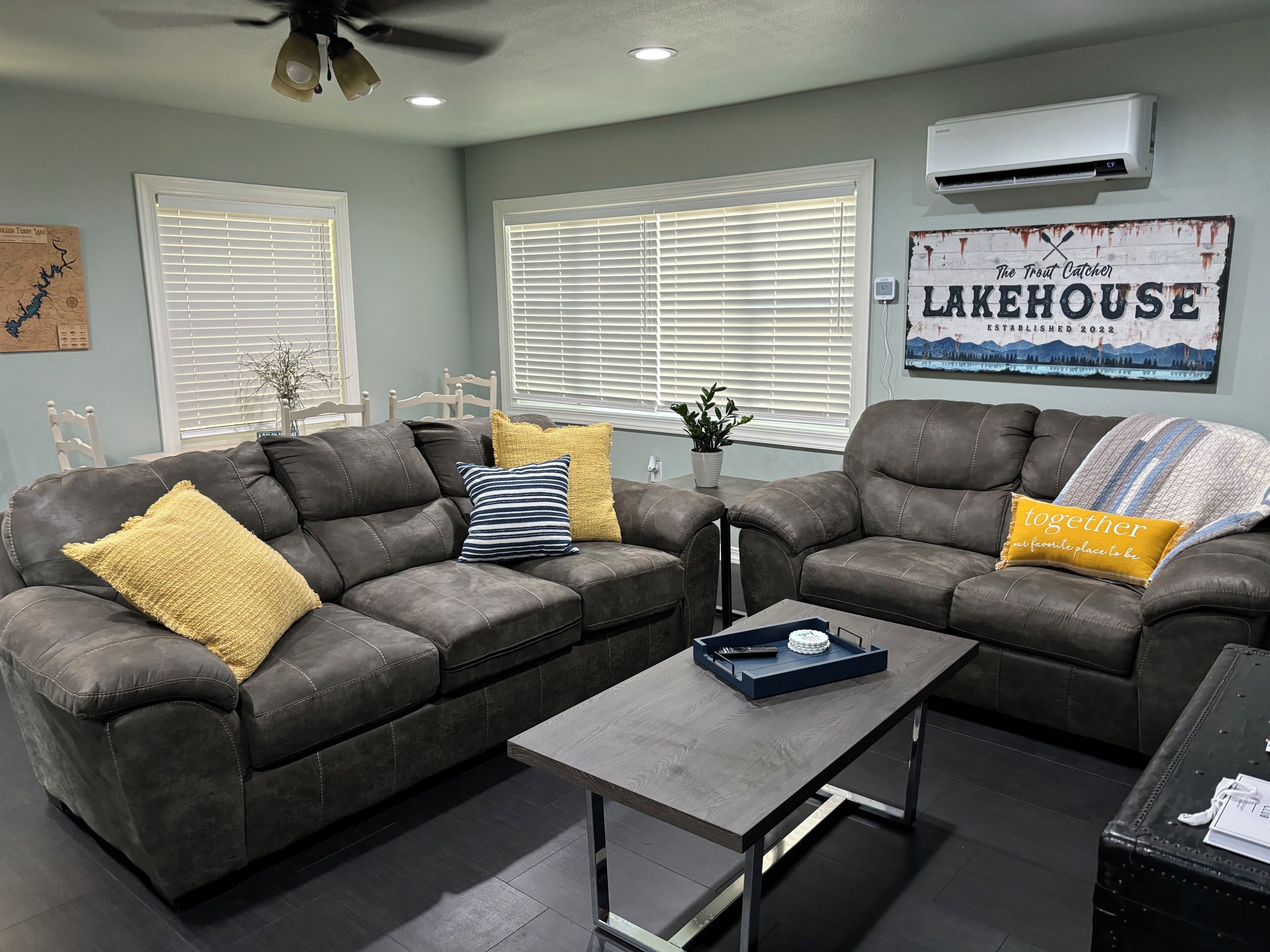 A modern living room with two leather sofas, a wooden coffee table, and a wall-mounted air conditioner.