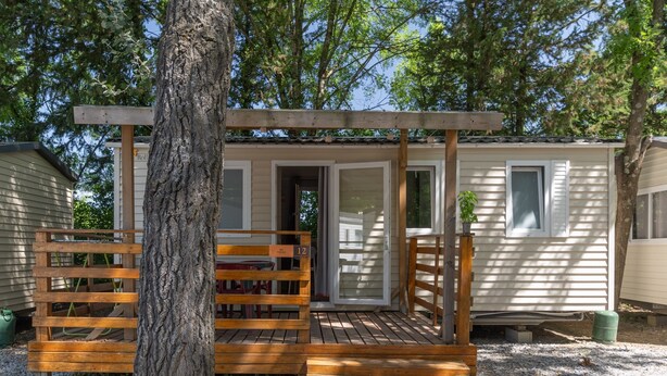 Una casa móvil con terraza de madera, un porche cubierto y una puerta que da al interior.