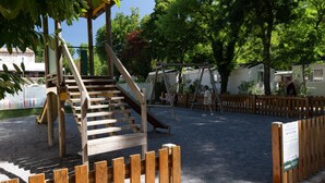 A playground with wooden structures, including a slide and swings, surrounded by a wooden fence. - Mobile Home 'Mobil-home Confort B - 1-8 Pers' with Shared Pool and Shared Garden (Lavilledieu)