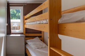 Ett rum med en våningssäng, ett fönster, ett litet skåp och utsikt över omgivningen.