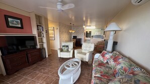 A living room with a television, sofa, chairs, and a small table.