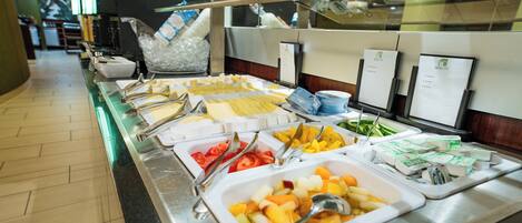 Een buffet met diverse etenswaren, zoals fruit, groenten en zuivelproducten.