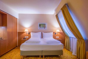 Une chambre d’hôtel avec un lit double, deux tables de chevet avec des lampes, une armoire en bois et un tableau au mur.
