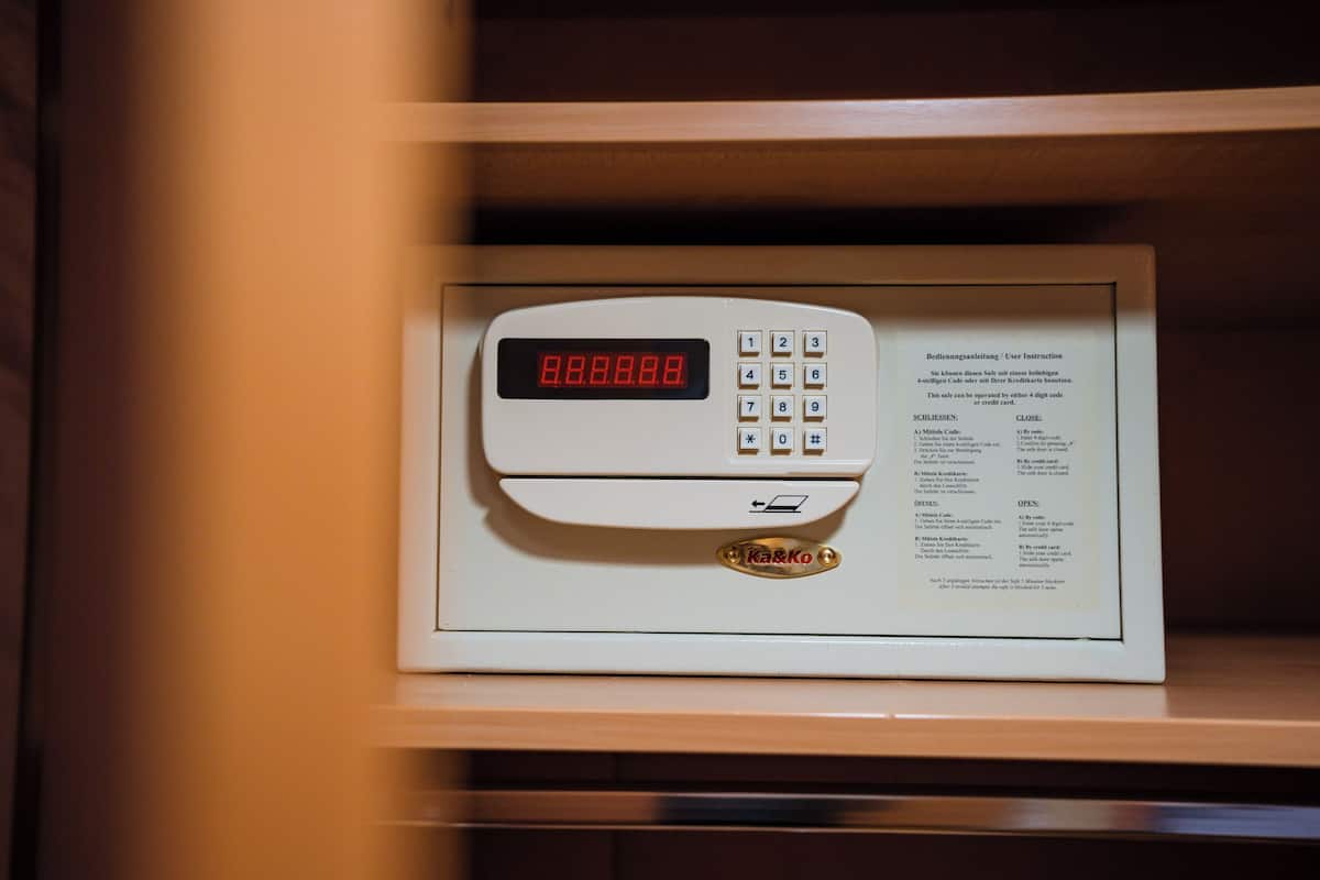 A digital safe with a keypad and a display screen, placed inside a wooden cabinet.