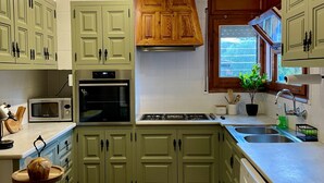 A kitchen with green cabinets, a microwave, oven, and a sink.