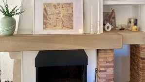 A fireplace with a mantel shelf, a framed picture, and a potted plant.