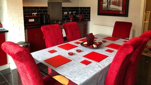 A dining area with a table set for six, red chairs, and a red and white tablecloth. - Sheffield Hillside Retreat (Sheffield)