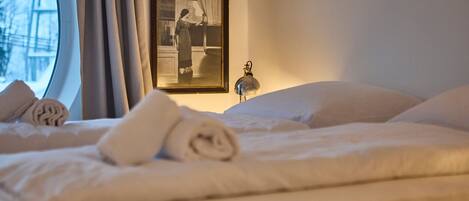 Een hotelkamer met een bed, een ingelijst beeld aan de muur en een raam met gordijnen.