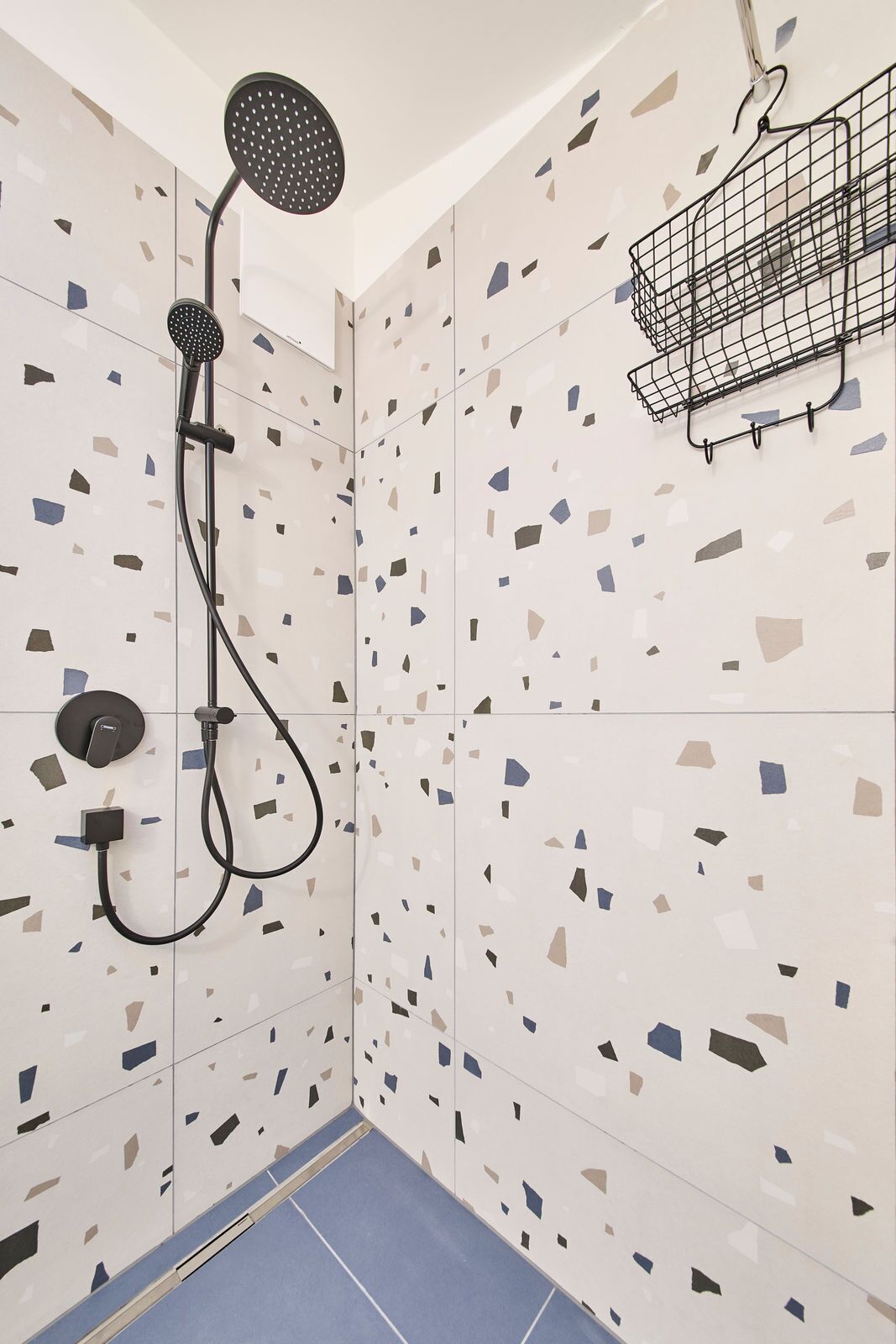 Une douche équipée d’un pommeau de douche à main et d’un panneau de commande fixé au mur.