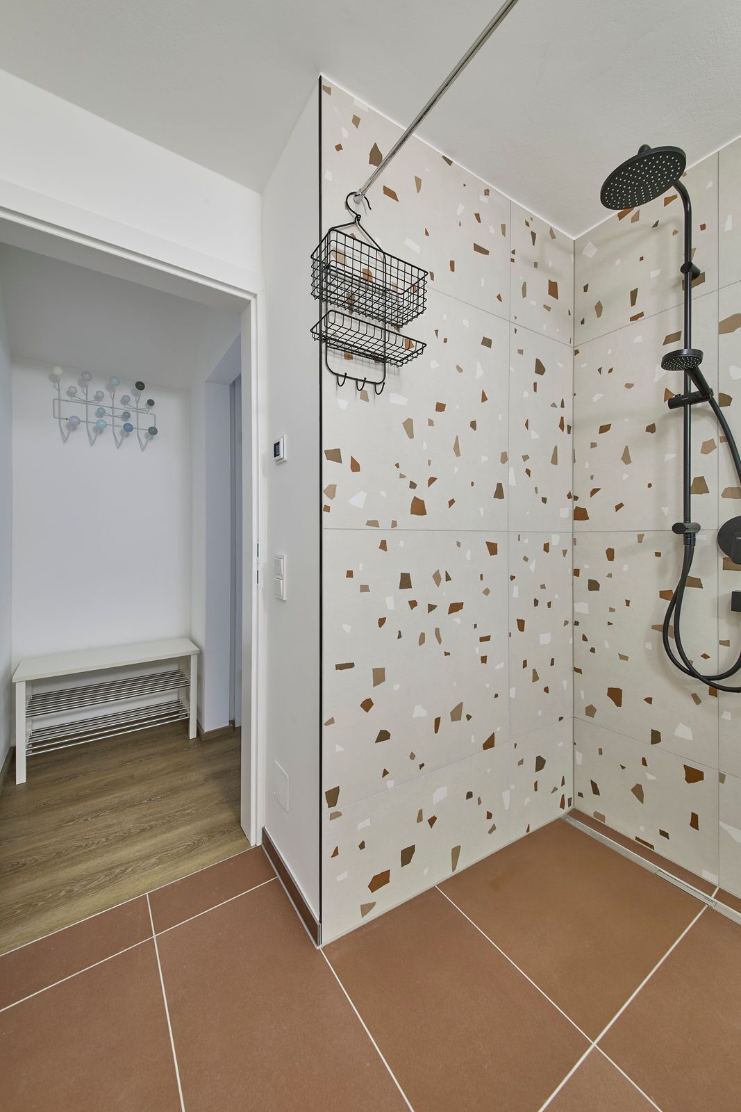 A bathroom with a shower, a bench, and a wall with a terrazzo pattern.