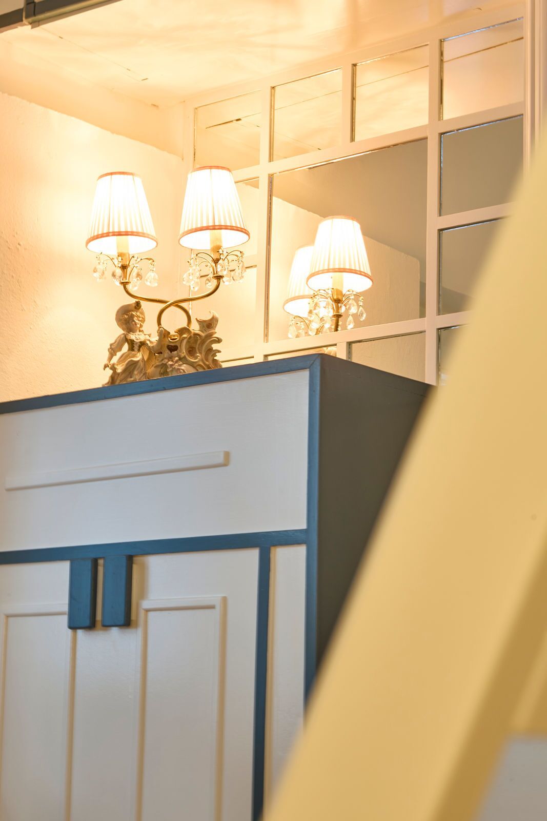 Un tocador de baño con espejo, dos lámparas de pared y una figura decorativa.
