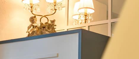 Un tocador de baño con espejo, dos lámparas de pared y una figura decorativa.