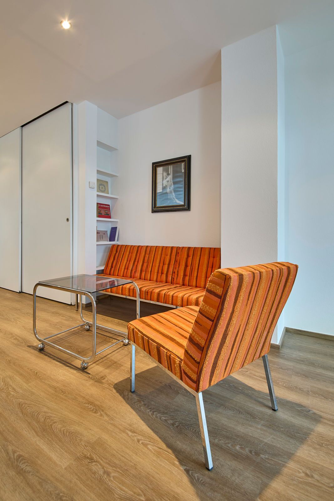 A modern living room with a sofa, a glass coffee table, and a bookshelf.
