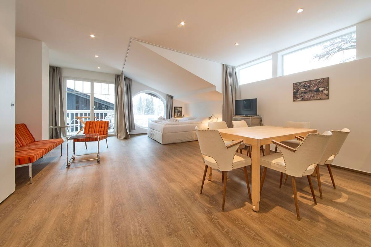 A spacious room with a dining area, a sofa, and a TV.