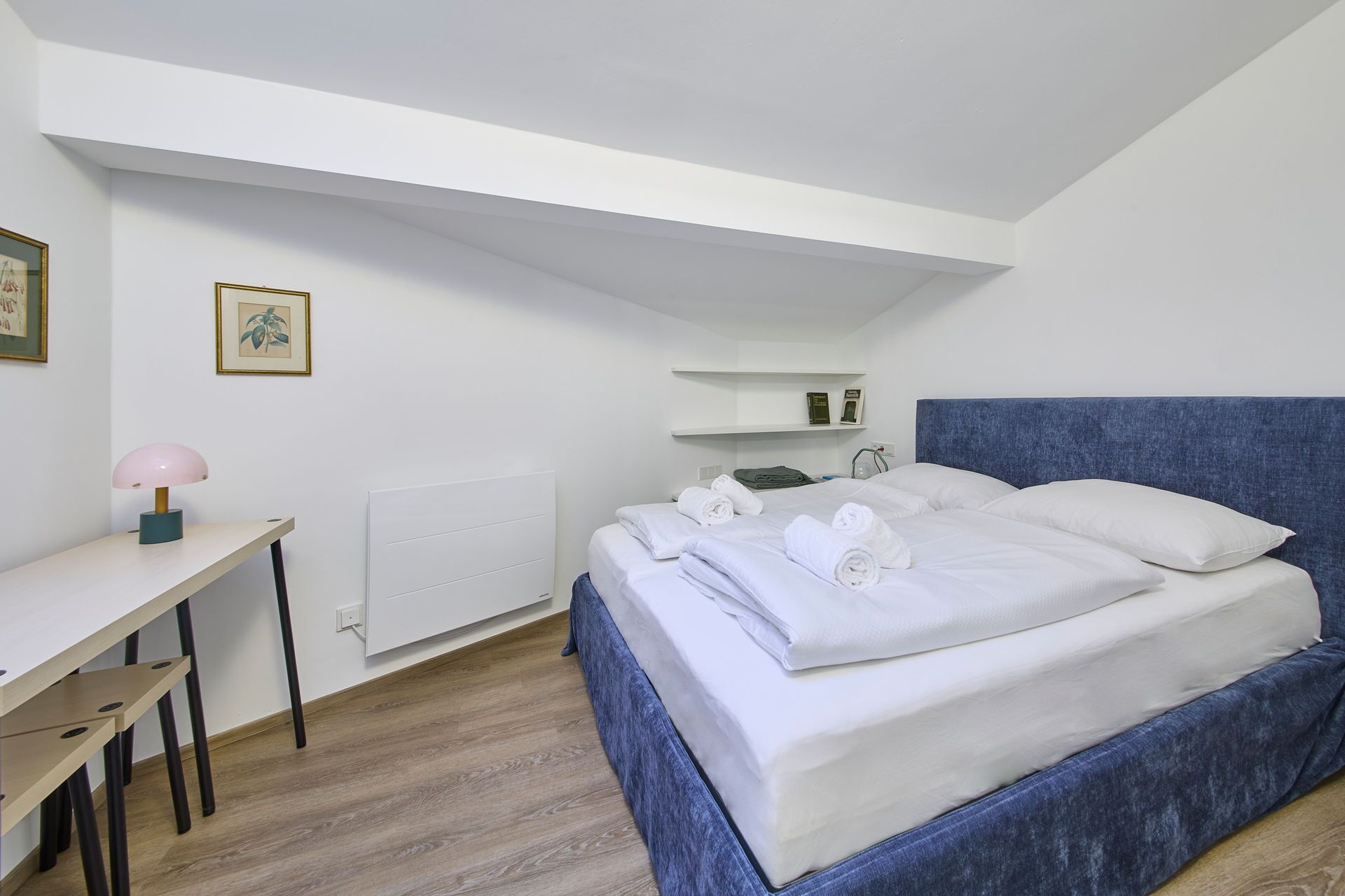 A bedroom with a bed, a desk, and a radiator.