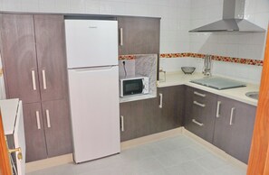 A kitchen with a white refrigerator, a microwave, and a sink.