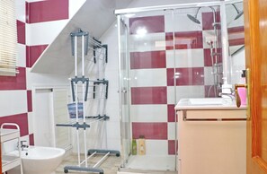 A bathroom with a glass shower enclosure, a white sink, and a mirror above the sink.