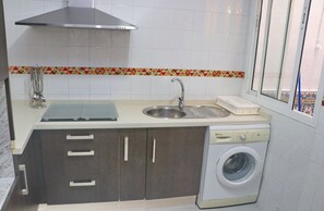 A compact kitchen with a sink, a washing machine, and a window.