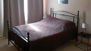 A bedroom with a bed, curtains, a wall-mounted lamp, and a small table. - Holiday Home with Pool, Mountain View, Wi-Fi and Air Conditioning (Callas)