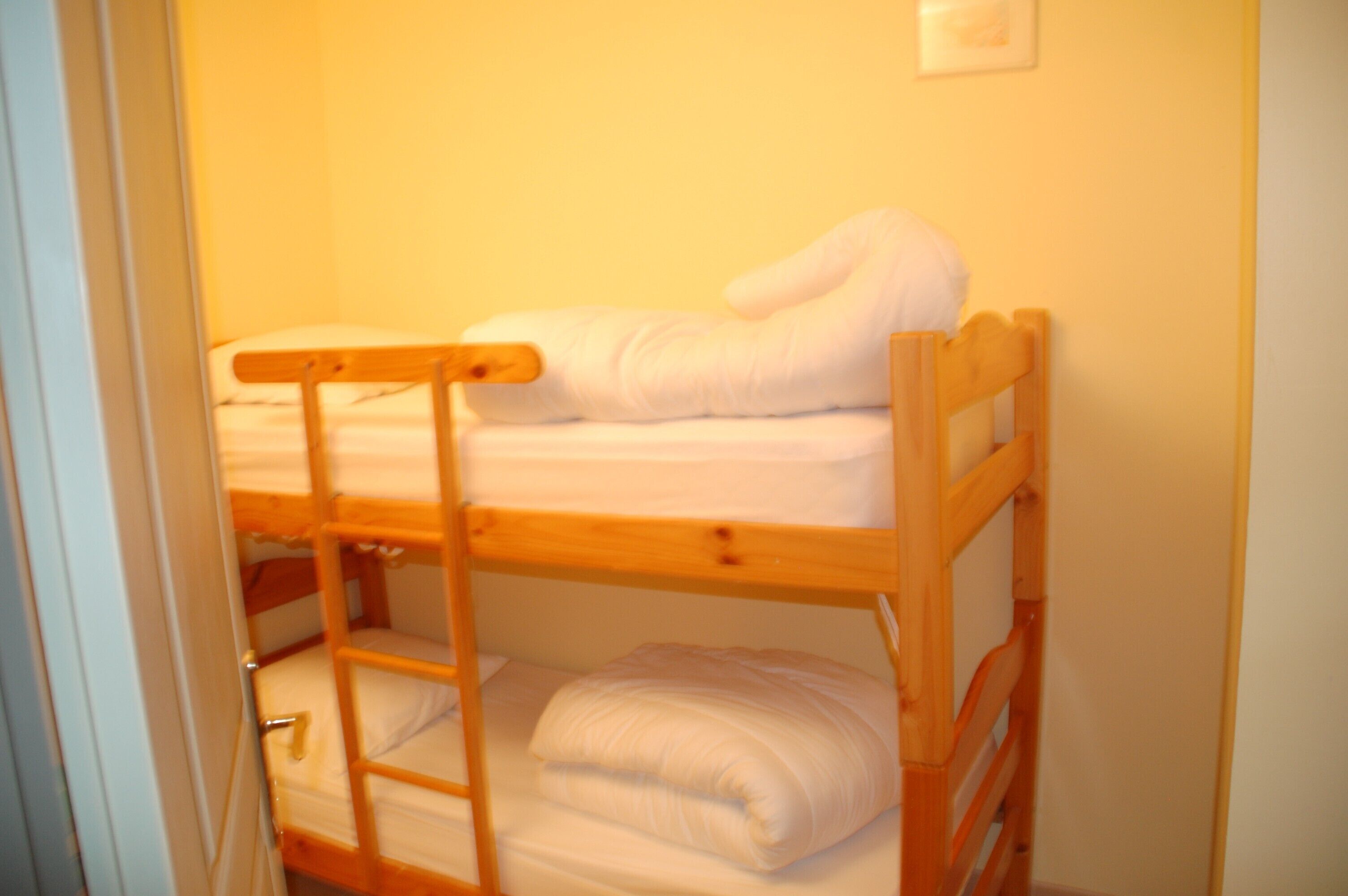 Un letto a castello con struttura in legno e biancheria bianca.