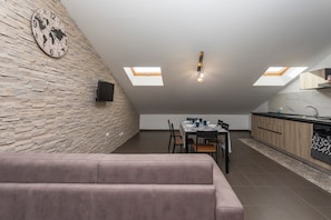 En moderne loftlejlighed med spiseplads, køkken og et stort vindue.