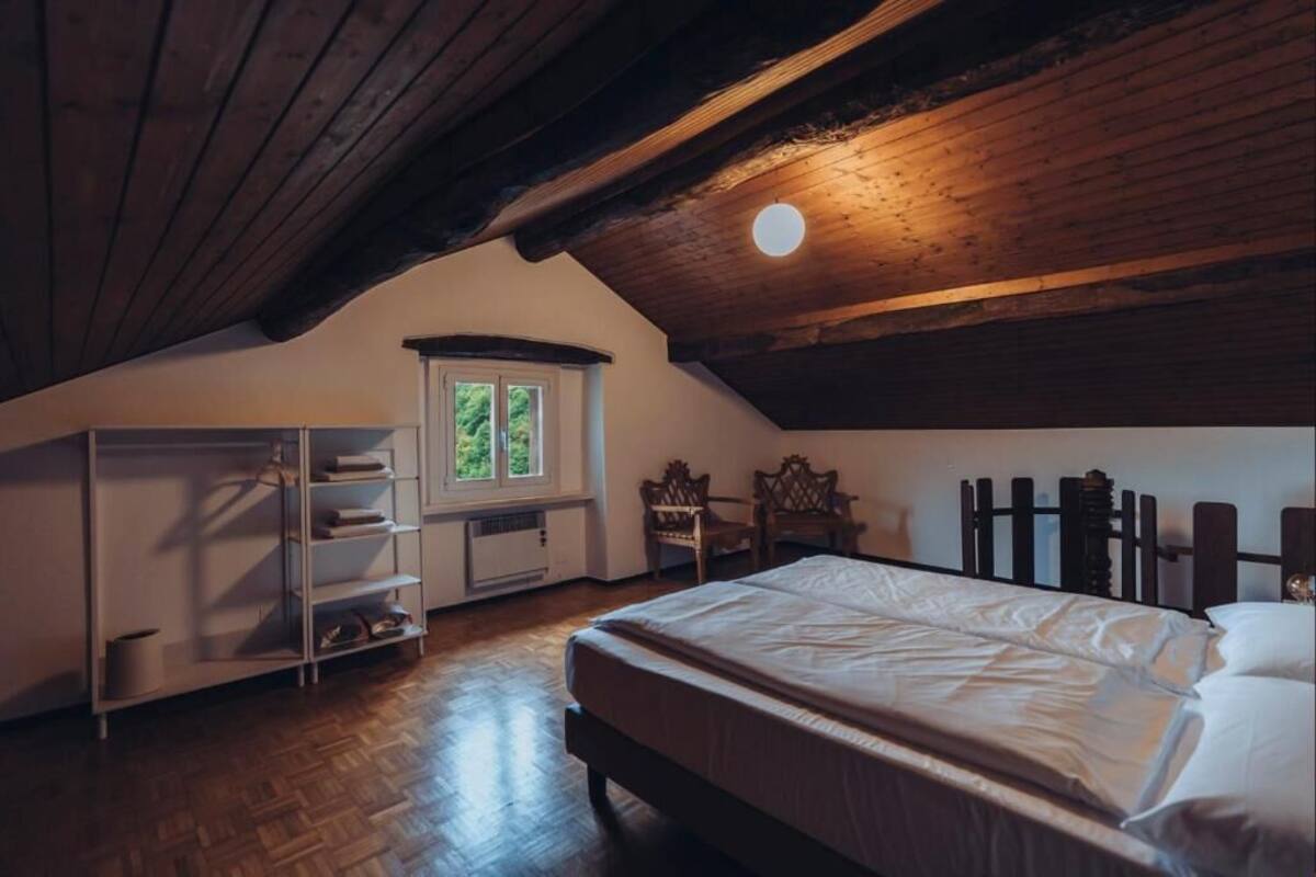 Un dormitorio con techo de madera, una cama, una ventana y una estantería empotrada.