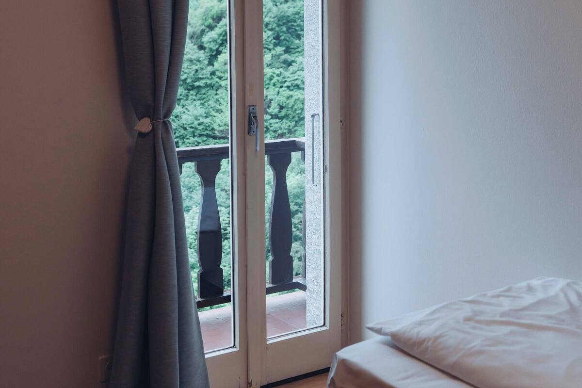 Una habitación con una cama, una ventana con cortinas y vistas al exterior.