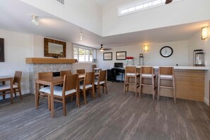 A spacious dining area with wooden tables and chairs, a fireplace, and a clock on the wall. - Ocean View Studio Unit Resting on Bluff in Beautiful Del Mar! (Del Mar)