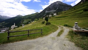 A rural mountain path leading to a small village with traditional houses and a church. - Baita Muffè Mountain apartment in a quiet and secluded area. (Lombardia)