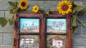 A rustic wooden sign with two framed paintings of houses and the words "Baita" and "Muffe" on it. - Baita Muffè Mountain apartment in a quiet and secluded area. (Lombardia)