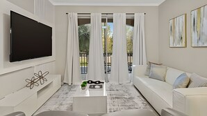 Un salon moderne doté d’un téléviseur à écran plat fixé au mur, d’un canapé blanc, d’une table basse agrémentée d’objets décoratifs et d’un balcon avec des rideaux.