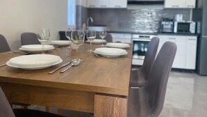 A modern dining area with a wooden table set for four, surrounded by grey chairs. - Vacation villa "Twin Garden" in Zánka, 5 minutes from Lake Balaton. Garden & Terrace. (Zánka)
