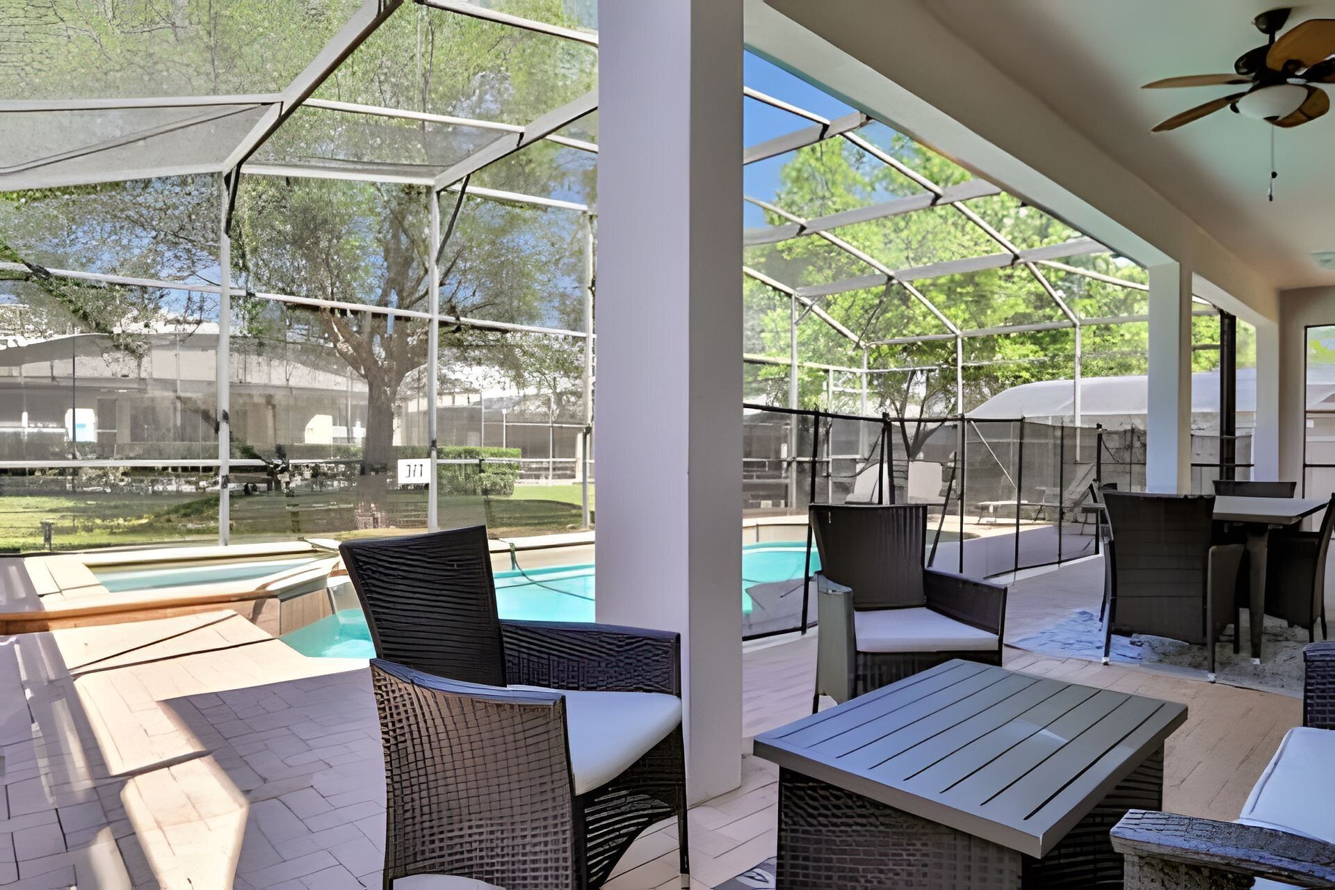 An outdoor patio with wicker furniture, a pool, and a covered area with a ceiling fan.