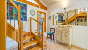 A wooden staircase with a cushioned chair, a cabinet with decorative items, and a mirror reflecting the staircase. - Guest Rooms 'La Palmeraie' with Sea View, Wi-Fi and Air Conditioning (Portiragnes)