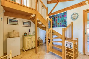 A wooden staircase leading to a loft, a white refrigerator, a cabinet with baskets, and a quilted wall hanging. - Guest Rooms 'La Palmeraie' with Sea View, Wi-Fi and Air Conditioning (Portiragnes)