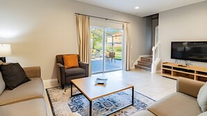 Una sala de estar moderna con sofá, sillón, mesa de centro y televisor.