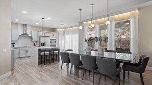 A modern kitchen with a central island, bar stools, and pendant lighting. - Windsor Hills 6BR Home, Private Pool + Game Room (Kissimmee)