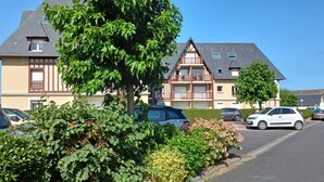 Un immeuble résidentiel de style architectural traditionnel, caractérisé par un toit à pignon et un balcon situé à l’étage supérieur.