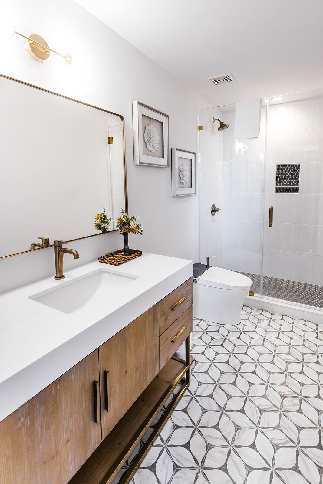Une salle de bain moderne avec un grand miroir, deux lavabos, une douche et un carrelage décoratif.