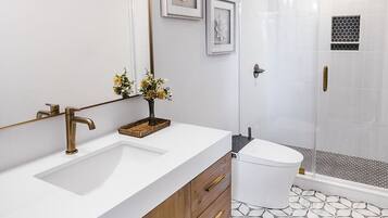 Une salle de bain moderne avec un grand miroir, deux lavabos, une douche et un carrelage décoratif.