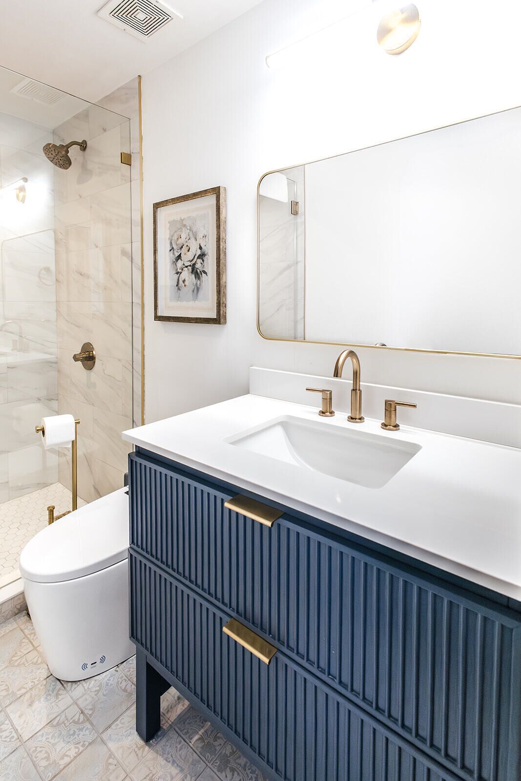 Et moderne badeværelse med en hvid vask, guldfarvede armaturer og et blått toiletbord.