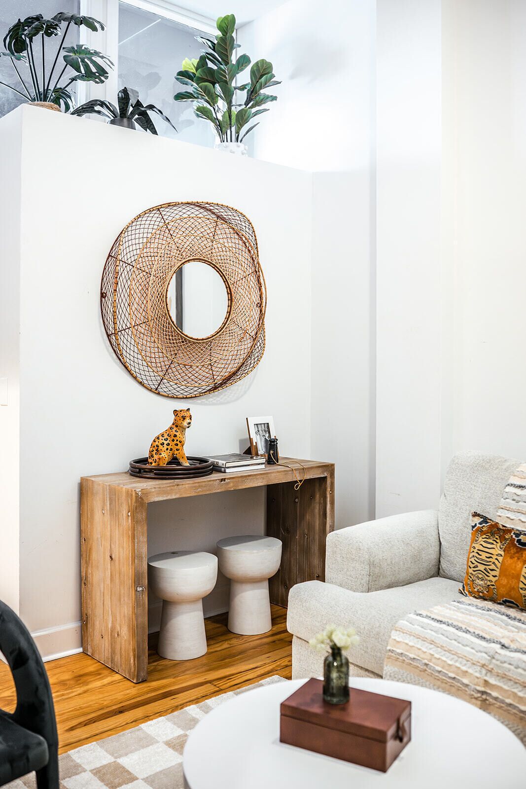 A modern living room with a wooden console table, a round mirror, and a leopard figurine.