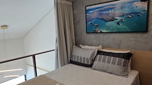 A modern hotel room with a large bed, a painting of a coastal scene, and a balcony with curtains. - Duplex 303B belavista by la playa (Ipojuca)